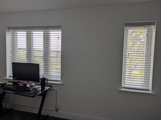 White faux wood Venetian blinds partially open in the study to reduce glare