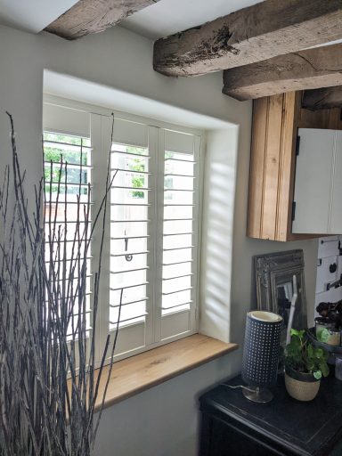 Off white window shutters fitted to a cottage kitchen