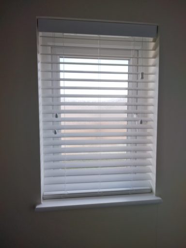 White faux wood Venetian blind in a bathroom window